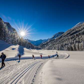 Langlaufers genieten van de vers geprepareerde loipe in de stralende zon in Steg, Liechtenstein.