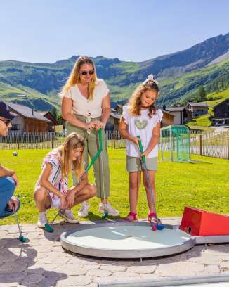 Een gezin speelt samen minigolf in het zonnige bergdorpje Malbun in Liechtenstein