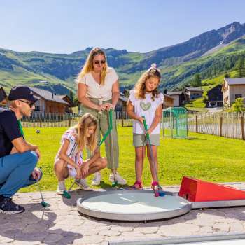 Gezinnen spelen samen minigolf in het zonnige bergdorp Malbun in Liechtenstein - plezier voor jong en oud in de Alpen.