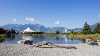 Natuurlijke zwemzone met zand, drijfhout en uitzicht op de omliggende bergen
