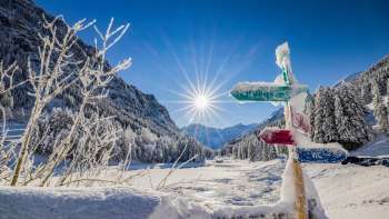 Besneeuwde wegwijzer in het Valüna langlaufgebied - Steg met stralende winterzon