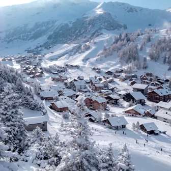 Besneeuwde huizen en skipistes in het alpenwinterdorp Malbun, gelegen in een prachtig berglandschap.