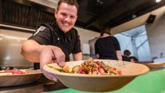 Chef-kok serveert een bord regionale gerechten op het Genussfestival Vaduz, Liechtenstein - culinair evenement met focus op genieten