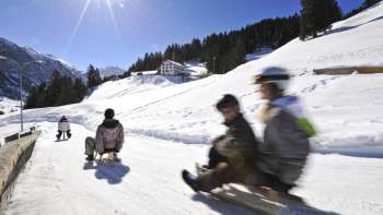 Leraren rodelen op de rodelbaan op een mooie zonnige dag in het winterlandschap