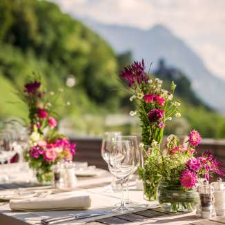Elegant gedekte tafel met bloemstukken op een terras met uitzicht op de Alpen - de perfecte achtergrond voor feesten of romantische diners in Liechtenstein