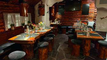 Uitzicht op een rustiek restaurant met houten meubels, tafels versierd in groen en kaarsen.