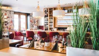 Het interieur van PUR Restaurant & Bar wordt gekenmerkt door elegante rood gestoffeerde stoelen en stijlvol gedekte tafels.