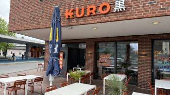 Buitenaanzicht van Restaurant Kuro met wijntafels in de buitenruimte op de voorgrond