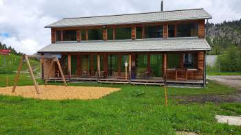 Buitenopname van de Malbipark-Bistro met een speeltuin en weiland op de voorgrond
