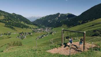 Een gezin geniet samen van het schommelen op het schommelpad in Malbun