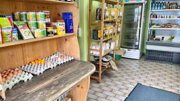  Binnenzicht van de boerderijwinkel van Aeulehof met rekken vol streekproducten, waaronder eieren en conserven.