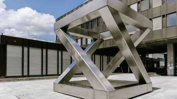 Geometrische sculptuur Z-Cube van Georg Malin in Vaduz - verspringende roestvrijstalen oppervlakken in de vorm van een kubus op een openbaar plein.