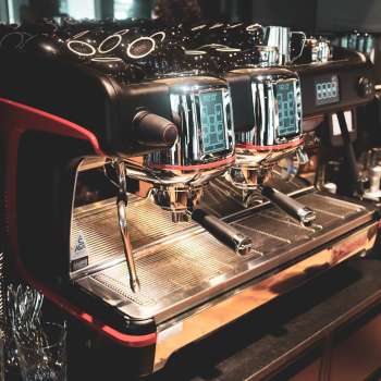 Koffiezetapparaat in het restaurant met glanzend roestvrijstalen oppervlak en rode accenten
