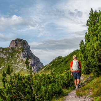 Wandelaars op een smal pad door bergdennen in Malbun, Liechtenstein met uitzicht op rotsachtige bergtoppen
