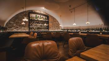 Sfeervol interieur van de WY Weinbar met verlichte barplanken, natuurstenen muur en elegant meubilair in de gewelfde kelder.