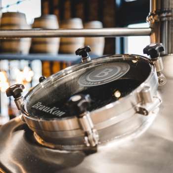 Close-up van een glimmende brouwketel met kijkvenster en brouwerijlogo in de Liechtensteinse brouwerij