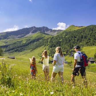 Een gezin wandelt door een bloeiende zomerweide in Malbun, Liechtenstein, en geniet van het uitzicht op de omringende Alpen.