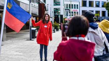 Stadsgids met Liechtensteinse vlag verwelkomt groep toeristen in Vaduz