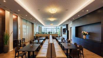 Lichte eetzaal in het Kommod restaurant met stijlvol design en grote ramen.