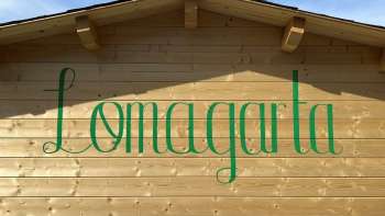 Zicht op het groene Lömagarta-logo, stijlvol aangebracht op de houten gevel van de gezellige biertuin.