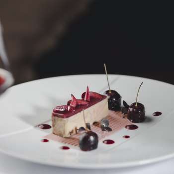 Elegant dessert op een wit bord, versierd met kersen en chocolade