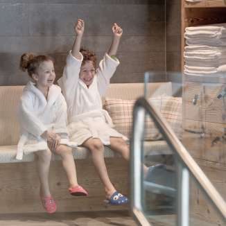 Twee kinderen in badjassen genieten van de wellnessruimte in Hotel Gorfion - gezinsvakanties met een feelgoodfactor in Malbun.