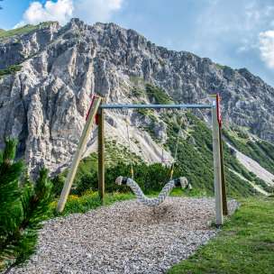 Hangschommel op het schommelpad Malbun met uitzicht op steile rotswanden en alpenlandschap in Liechtenstein
