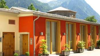 Buitenaanzicht van het Cultureel Centrum Gasometer met kleurrijke gevel en Alpenpanorama op de achtergrond.