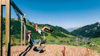 Twee schommelende kinderen met uitzicht op Malbun