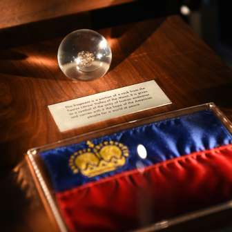 Tentoonstelling in de Schatkist van Liechtenstein: Liechtensteinse vlag met gouden kroon en glazen bol met historisch artefact