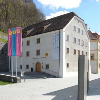 Buitenaanzicht van het Nationaal Museum van Liechtenstein met vlaggen op de voorgrond