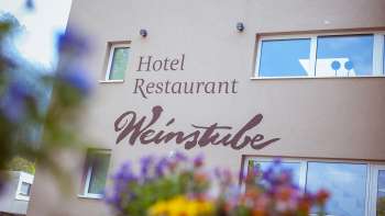 Zicht op restaurant Weinstube met bloemen op de voorgrond 