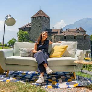 Vrouw zittend op een bank met uitzicht op kasteel Vaduz en de bergen van Liechtenstein, moderne buitensfeer met decoratie
