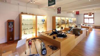 Tentoonstelling in het Lawena Museum met vitrines, oude huishoudelijke apparaten en een historische collectie stofzuigers.