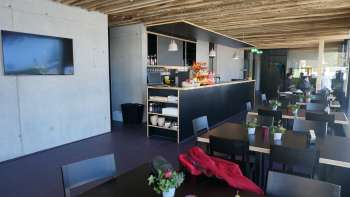 Moderne eetkamer met donkere tafels, verse bloemstukken en een rustiek houten dak