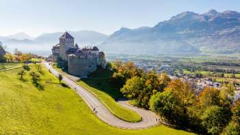 Kasteel Vaduz op een heuvel met uitzicht op de Rijnvallei en de omliggende bergen.