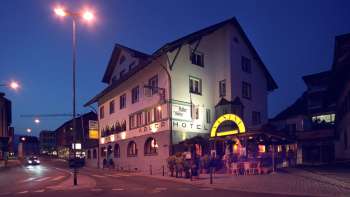 Buitenaanzicht van restaurant Adler 's avonds, met traditionele gevel en sfeervolle verlichting