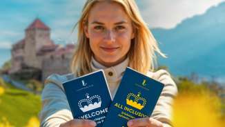 Vrouw presenteert de "WELCOME Belevenispas" en "ALL INCLUSIVE Belevenispas" voor het kasteel van Vaduz