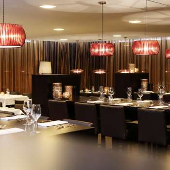 Stijlvolle eetkamer met donkere meubels, rode designlampen en een elegante sfeer
