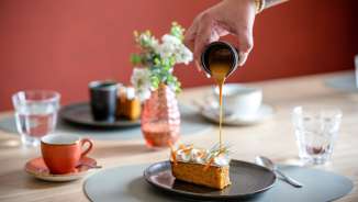 Hand giet karamelsaus over een dessert in het stijlvolle restaurant RUUF in het b_smart Hotel Kloster Schaan in Liechtenstein