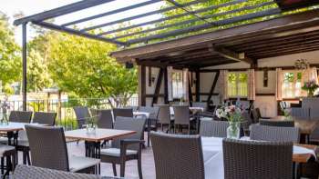 Uitnodigende buitenruimte met rustiek houten interieur, gedekte tafels en bloeiende bloemen