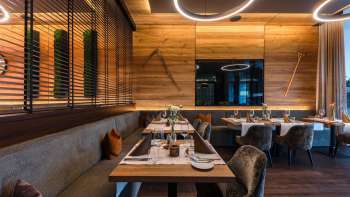 Modern restaurantgedeelte met mooie houten meubels, elegante tafels en comfortabele fauteuils.