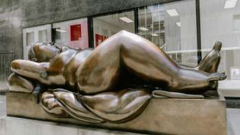 Voluptueuze vrouwenfiguur van brons - het kunstwerk "Liggende vrouw" van Fernando Botero als blikvanger in het stadscentrum.