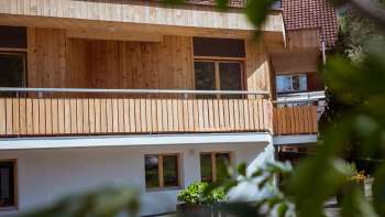Buitenaanzicht van het pension op Camping Mittagsspitze met houten gevel en balkon in een natuurlijke omgeving.
