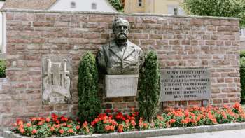 Rheinberger monument in Vaduz met rode bloemen eronder