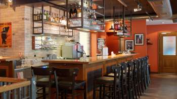 orn bar in het New Castle Vaduz met een lange houten toonbank, hoge krukken en hangende glazen planken in een warme sfeer.