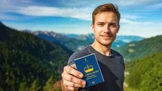 Man toont de "ALL INCLUSIVE Belevenispas" met bergpanorama op de achtergrond