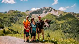Familie poseert met een adelaar in de zomer tegen de indrukwekkende achtergrond van de bergen van Malbun in Liechtenstein.