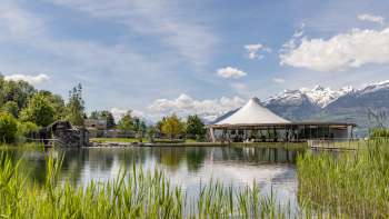 Modern paviljoen aan het water in Recreatiecentrum Grossabünt in Liechtenstein, omgeven door natuur en met uitzicht op de Alpen.