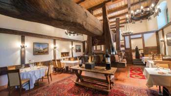 Rustieke eetzaal met historische houten balken, open haard en gedekte tafels in restaurant Torkel.